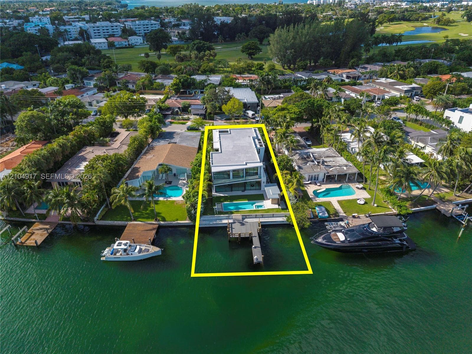 Waterfront property featuring a multi-level structure with expansive glass facades, a private swimming pool, and a dedicated boat dock