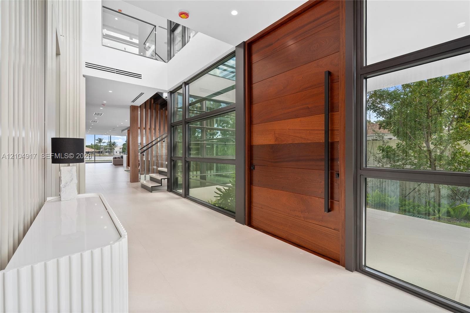 Grand entry featuring a large wood-panel door, floor-to-ceiling glass panels, and a two-story foyer
