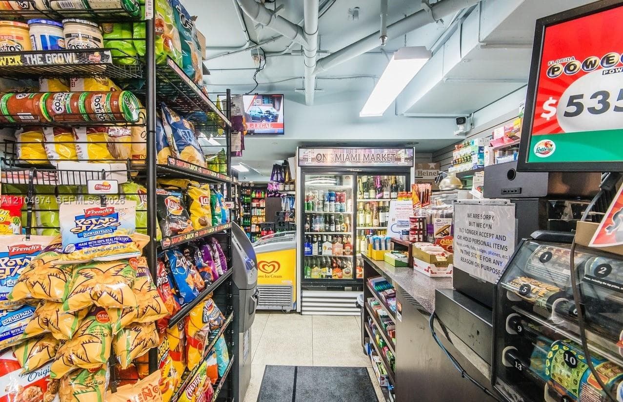 Commercial space featuring tile flooring, metal shelving units, integrated glass-door refrigeration, and a service counter