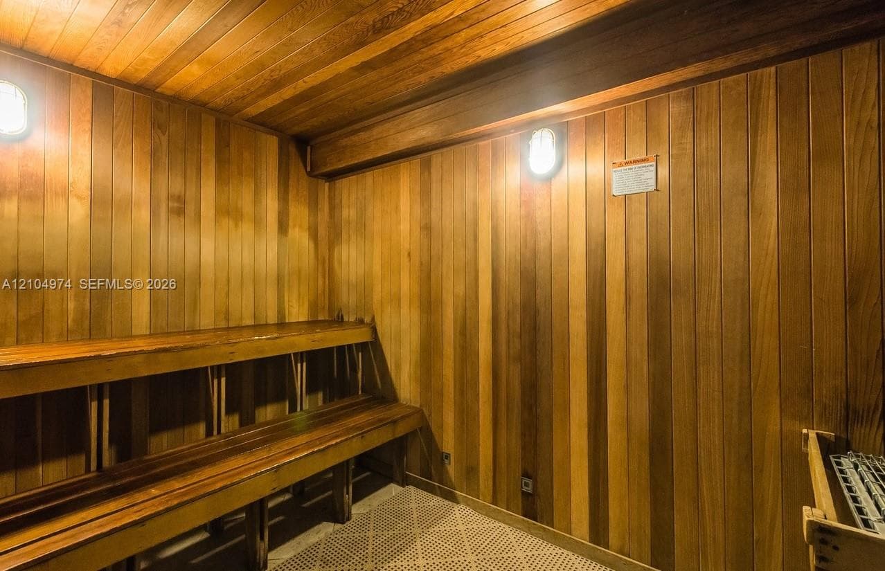 Sauna featuring cedar paneling, multi-level wood bench seating, and wall-mounted light fixtures