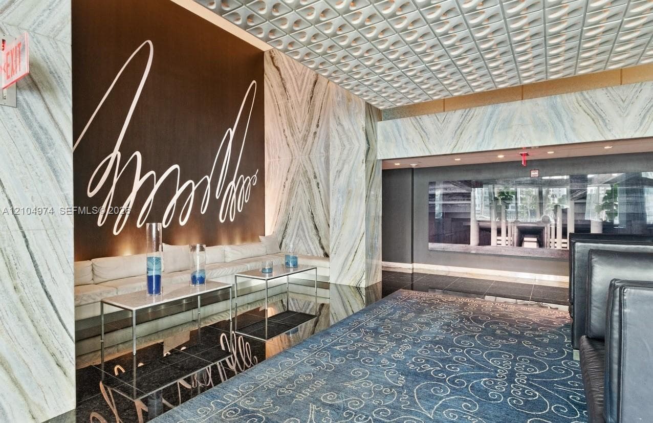 Grand lobby featuring book-matched stone wall panels, high-contrast dark stone flooring, and intricate textured ceiling detailing