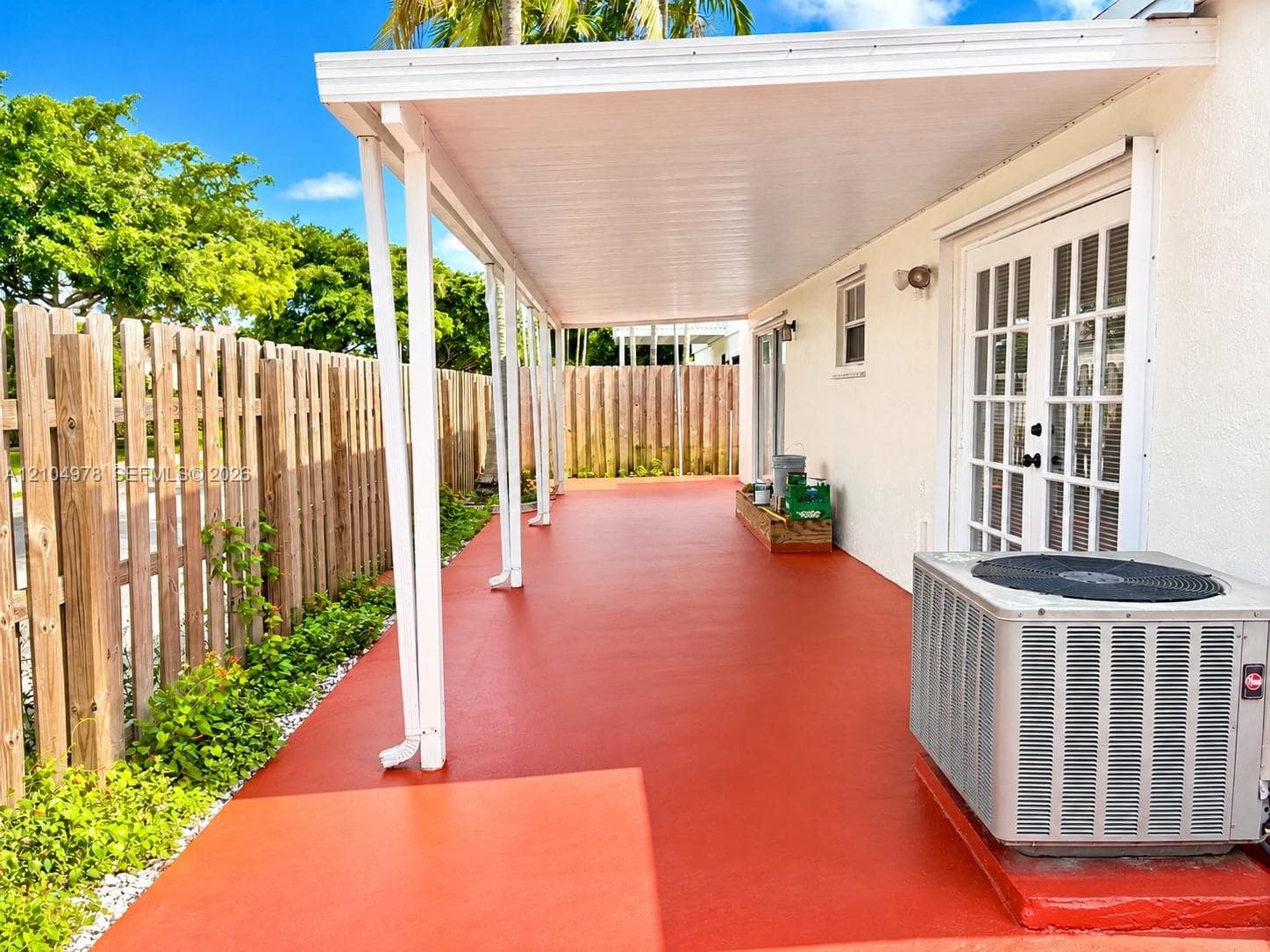 Expansive patio with a red-toned surface and a covered overhang