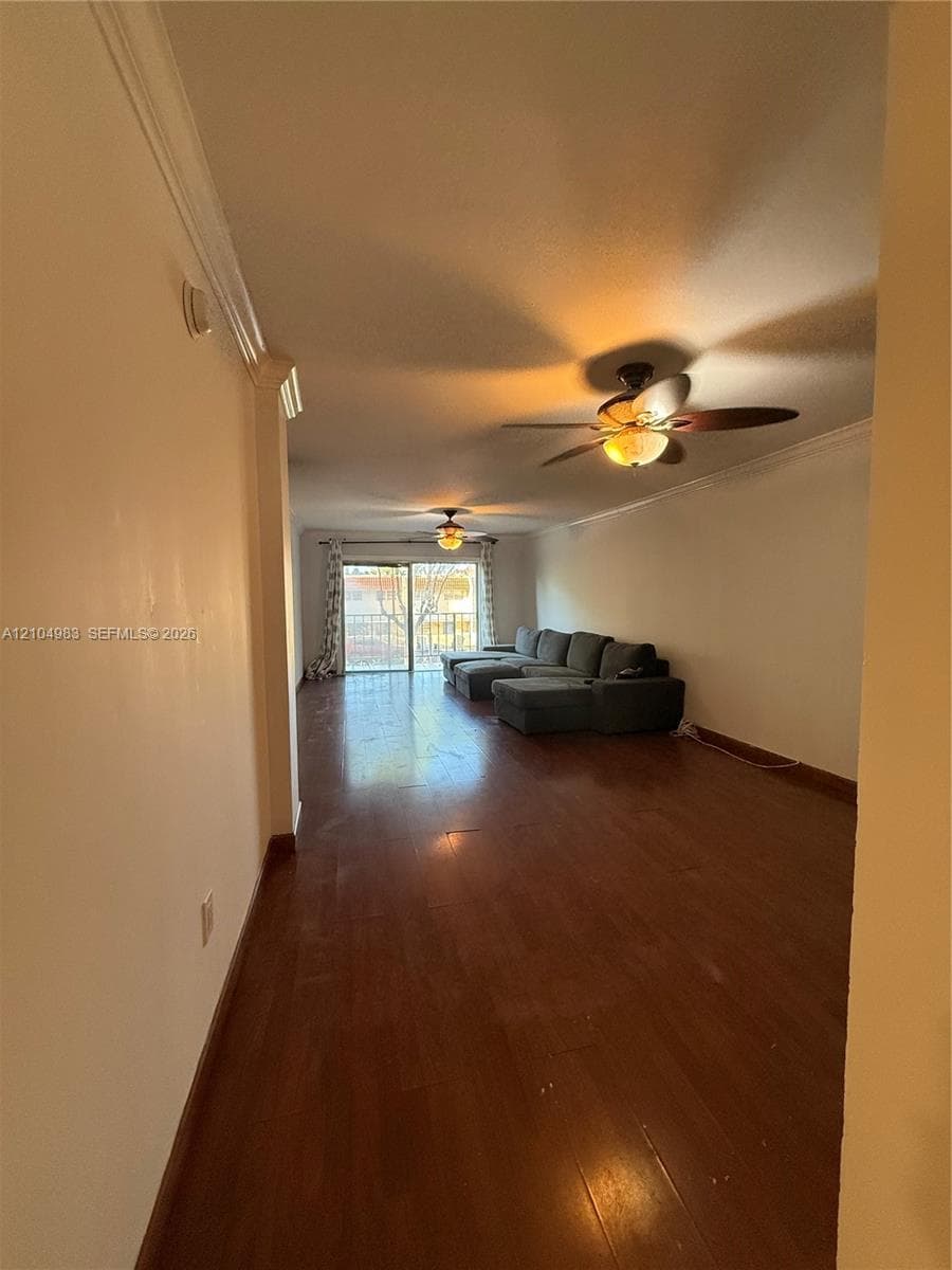 Wood-finish flooring, dual ceiling fans with integrated light fixtures, crown molding, and glass sliding doors