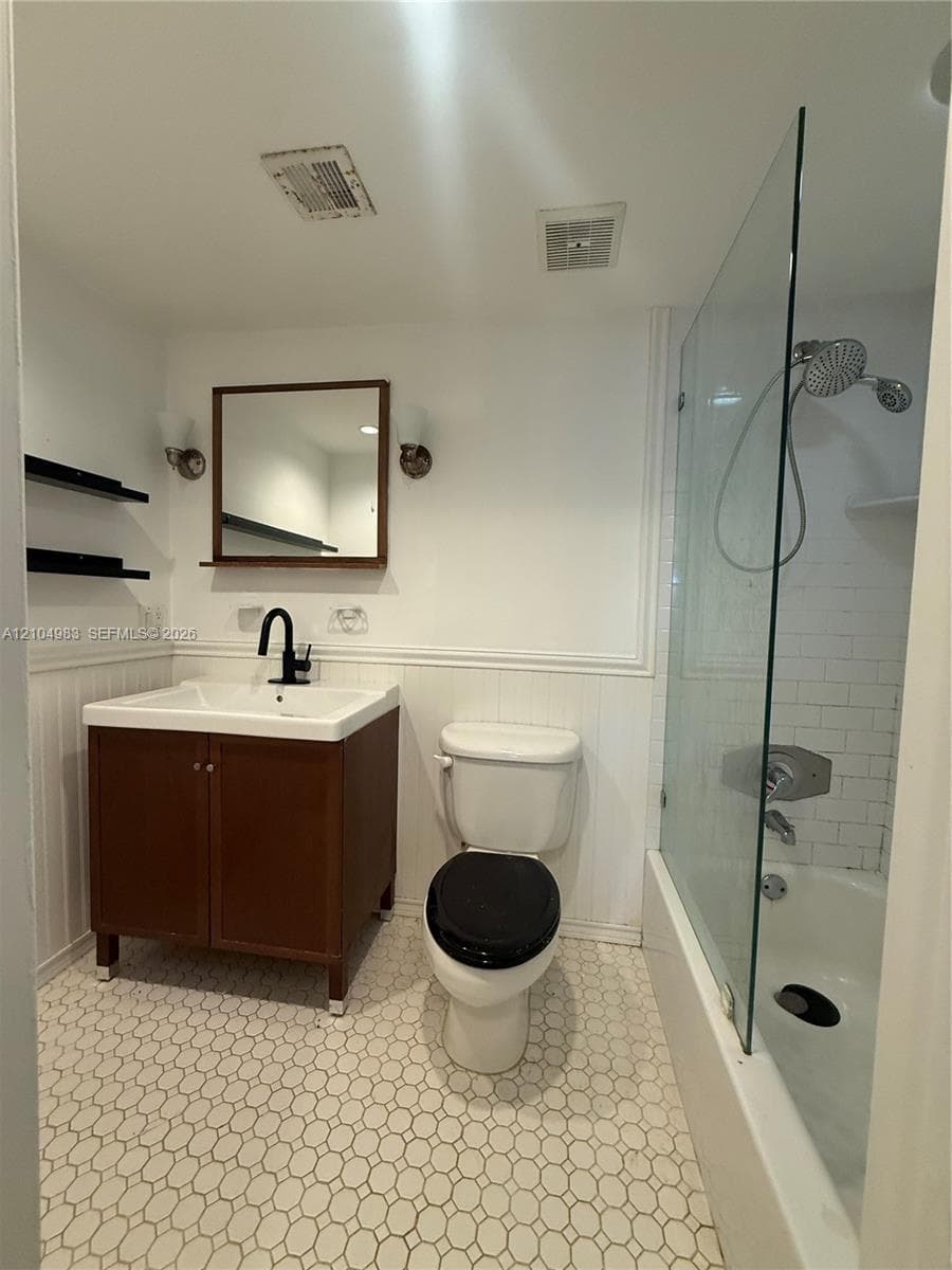 Bathroom featuring a vanity with an integrated basin, matte black faucet, frameless glass shower enclosure, subway tile shower surround, and hexagonal tile flooring