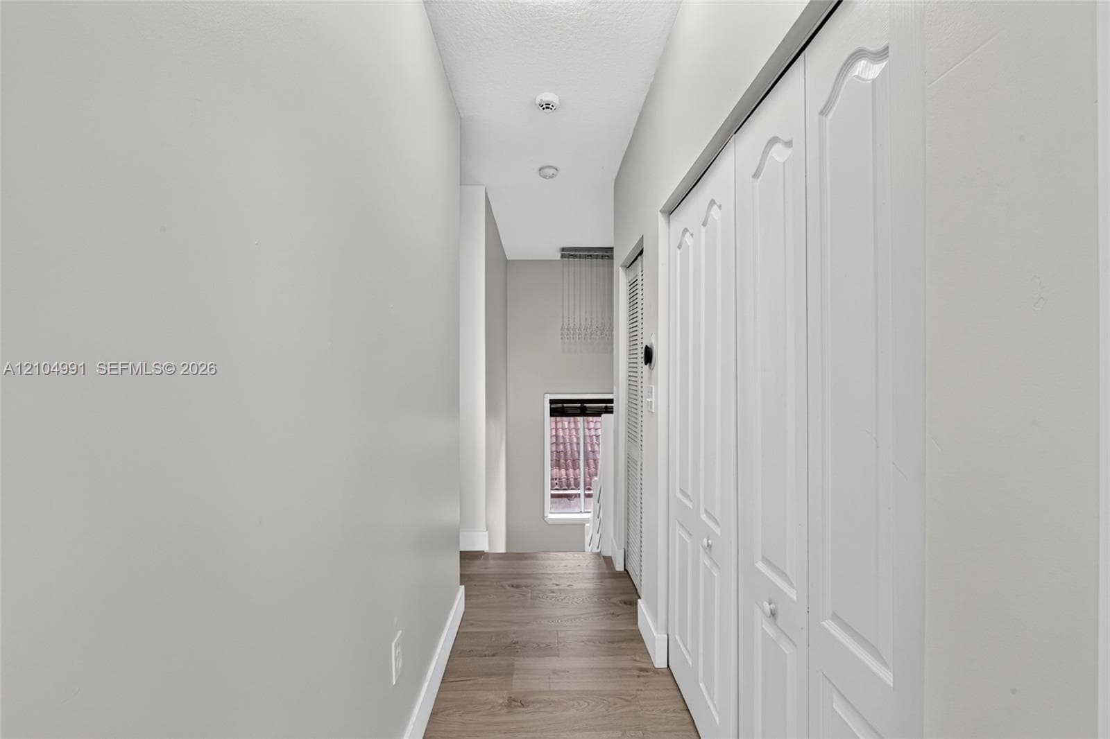 Hallway featuring wood-finish flooring, white paneled closet doors, and recessed ceiling lighting