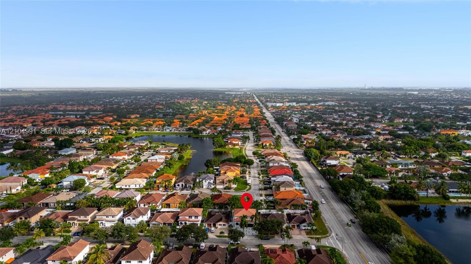 Aerial perspective of a residential neighborhood featuring multiple ponds and expansive surrounding landscape