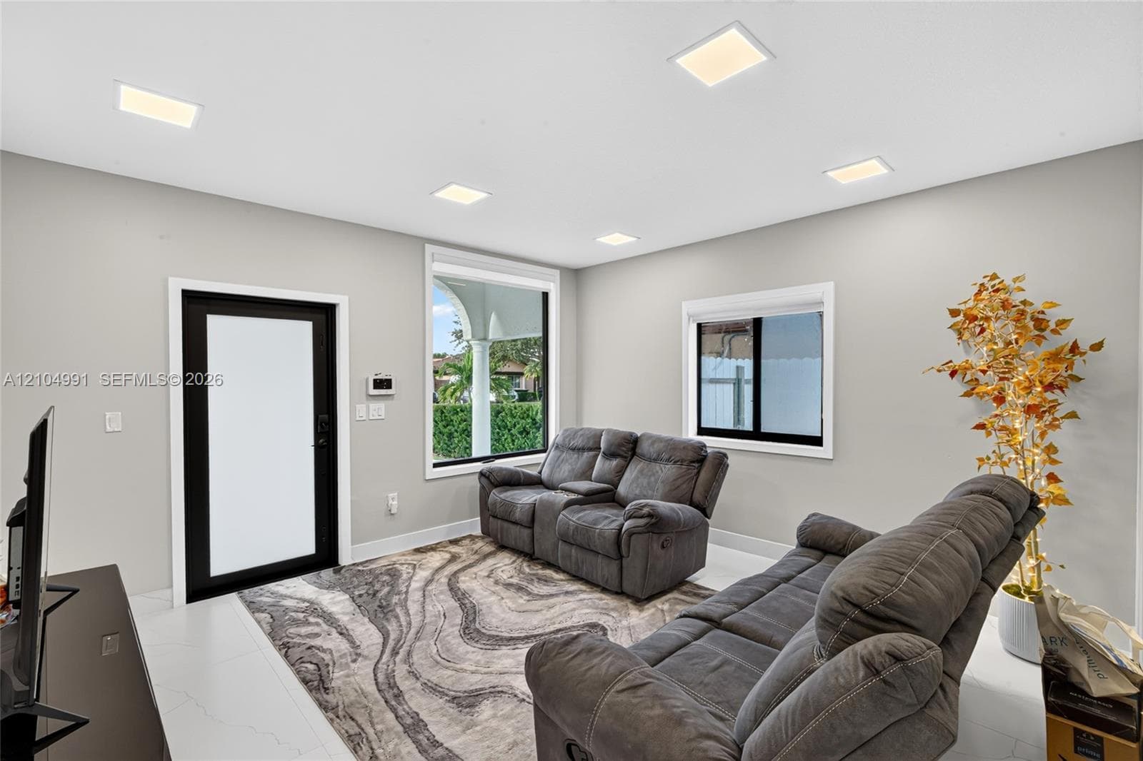 Interior space featuring neutral wall paint, recessed lighting, large-format tile flooring, and a contrast-framed exterior door