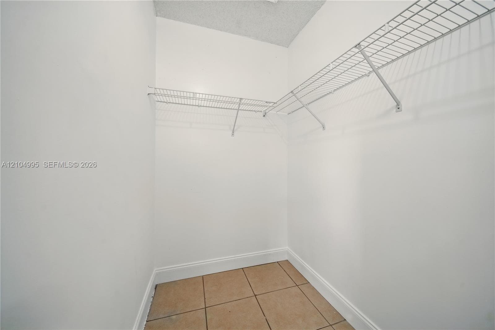 Storage area featuring ceramic tile flooring, neutral wall finishes, and integrated white wire shelving