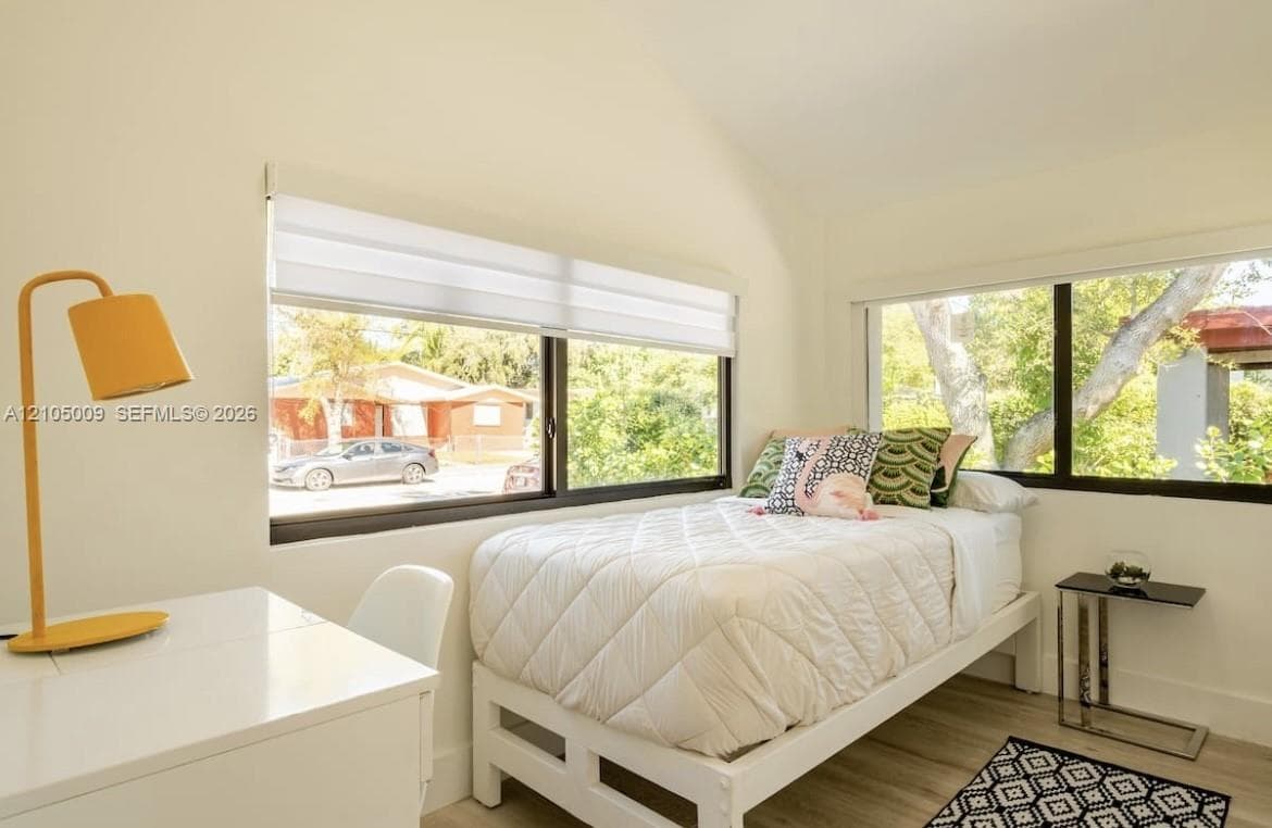 Wood-finish flooring, white walls, and multiple windows with roller shades