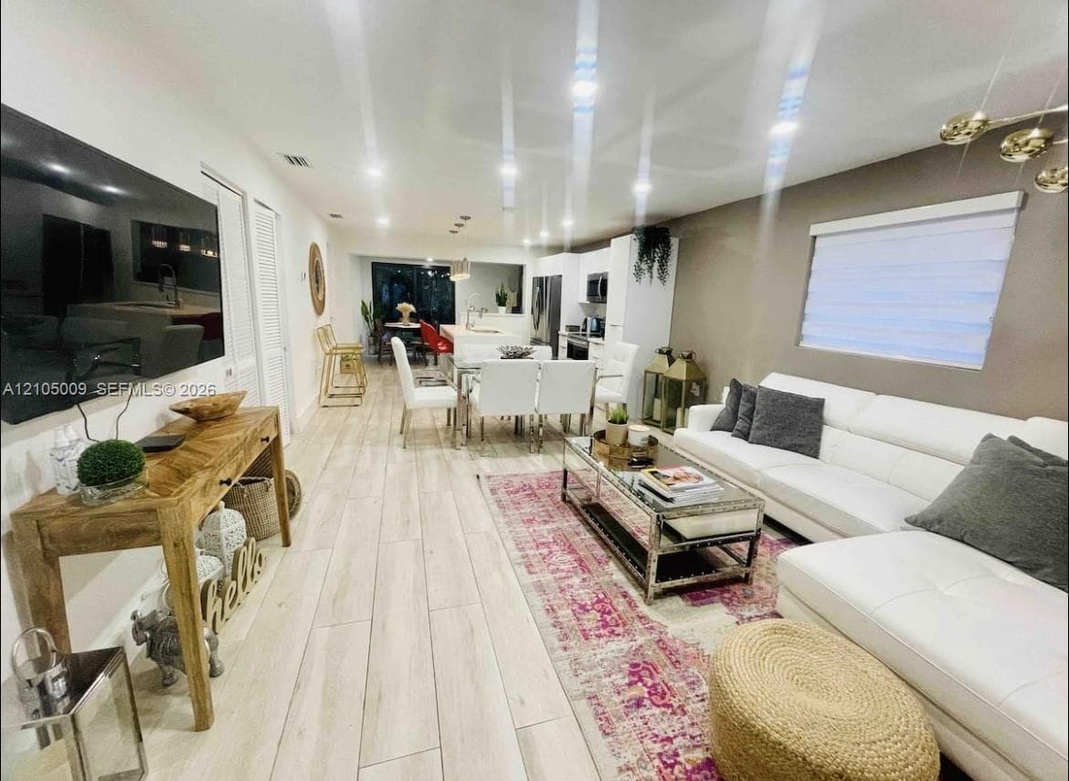 Open-concept living area with wood-finish flooring, recessed lighting, and a neutral color palette