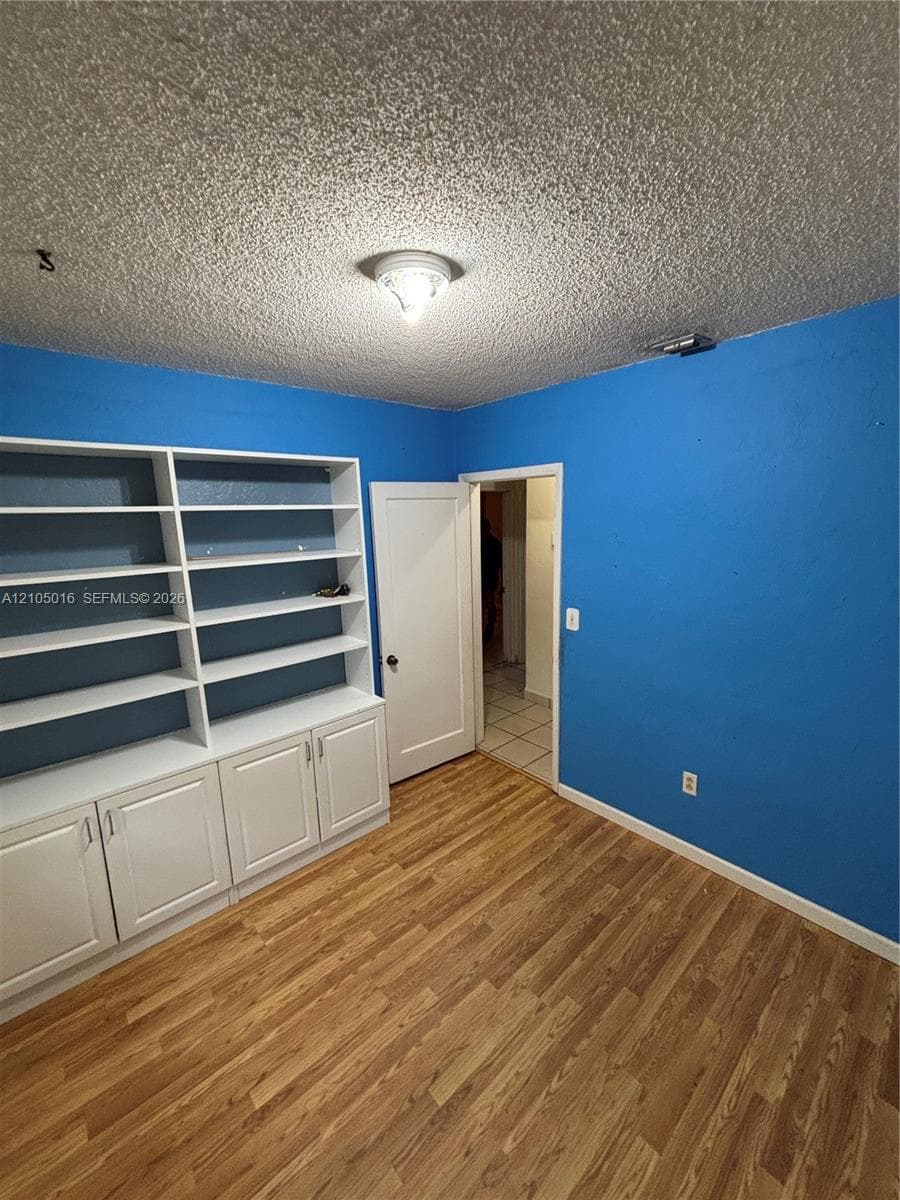 Built-in white cabinetry with open shelving, wood-finish flooring, and overhead lighting