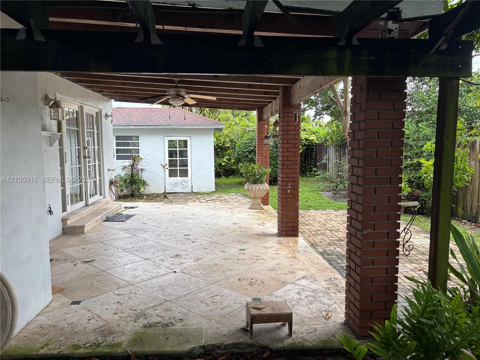 Expansive patio featuring large format tile, a wood pergola, and brick columns