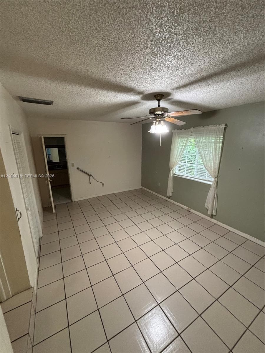Tiled flooring throughout, ceiling fan with integrated lighting, and a window with natural light
