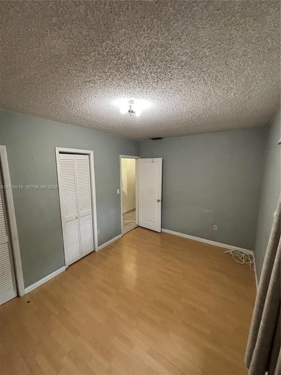 Wood-finish flooring, neutral wall paint, and white bi-fold closet doors
