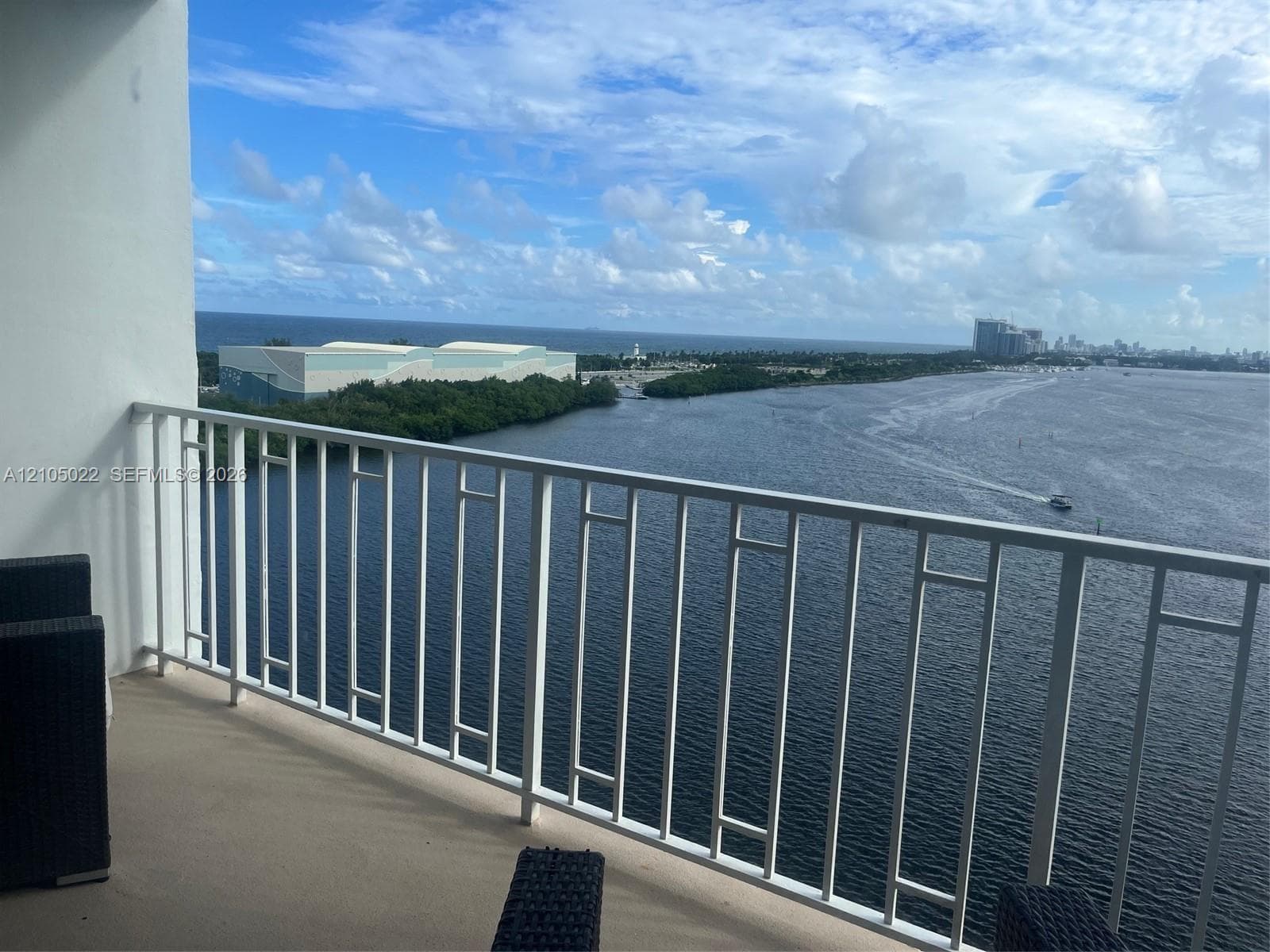 Balcony featuring a white metal railing and a water backdrop with distant buildings