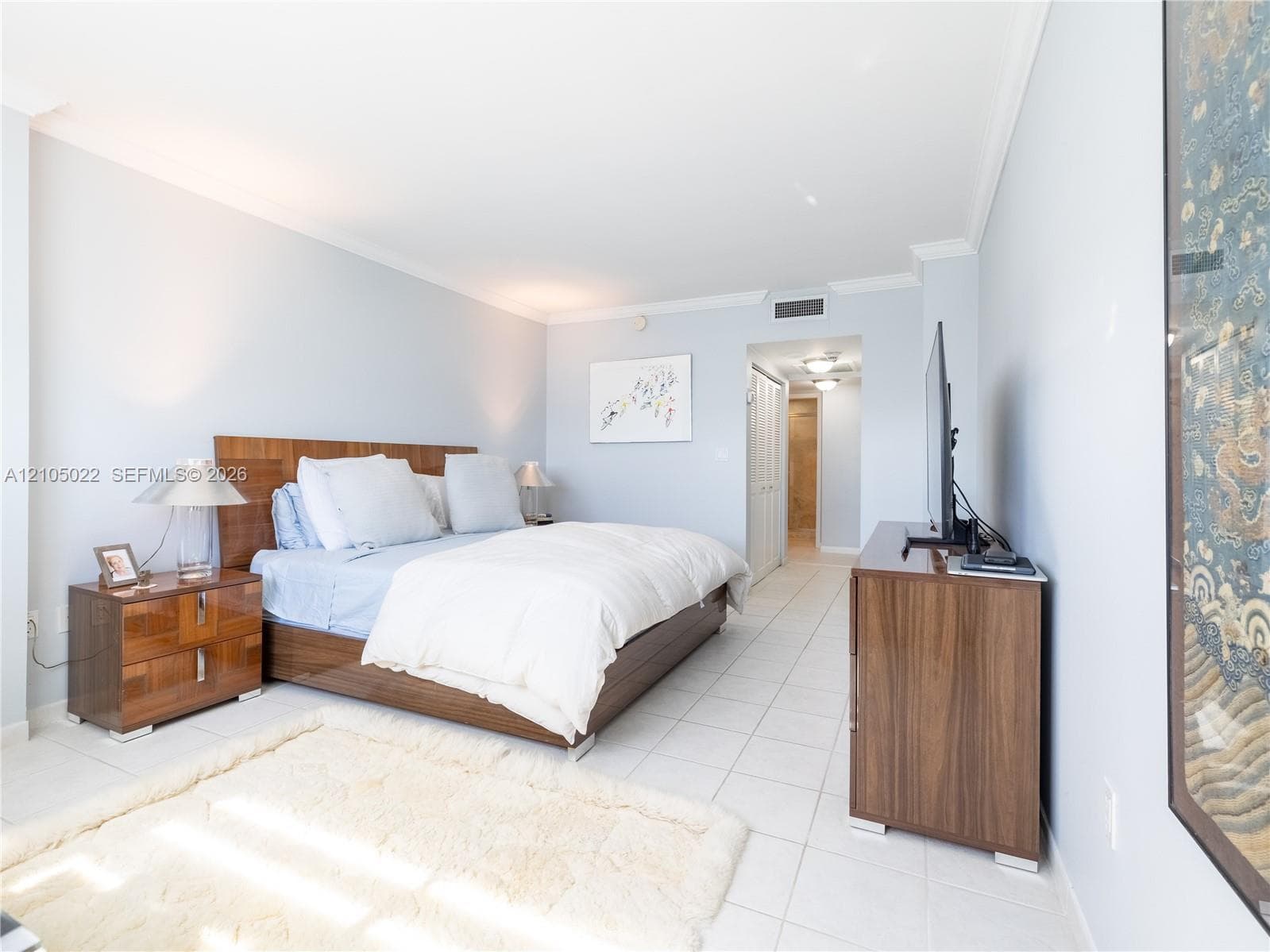 Tile flooring extends throughout the space, complemented by crown molding and light-colored walls