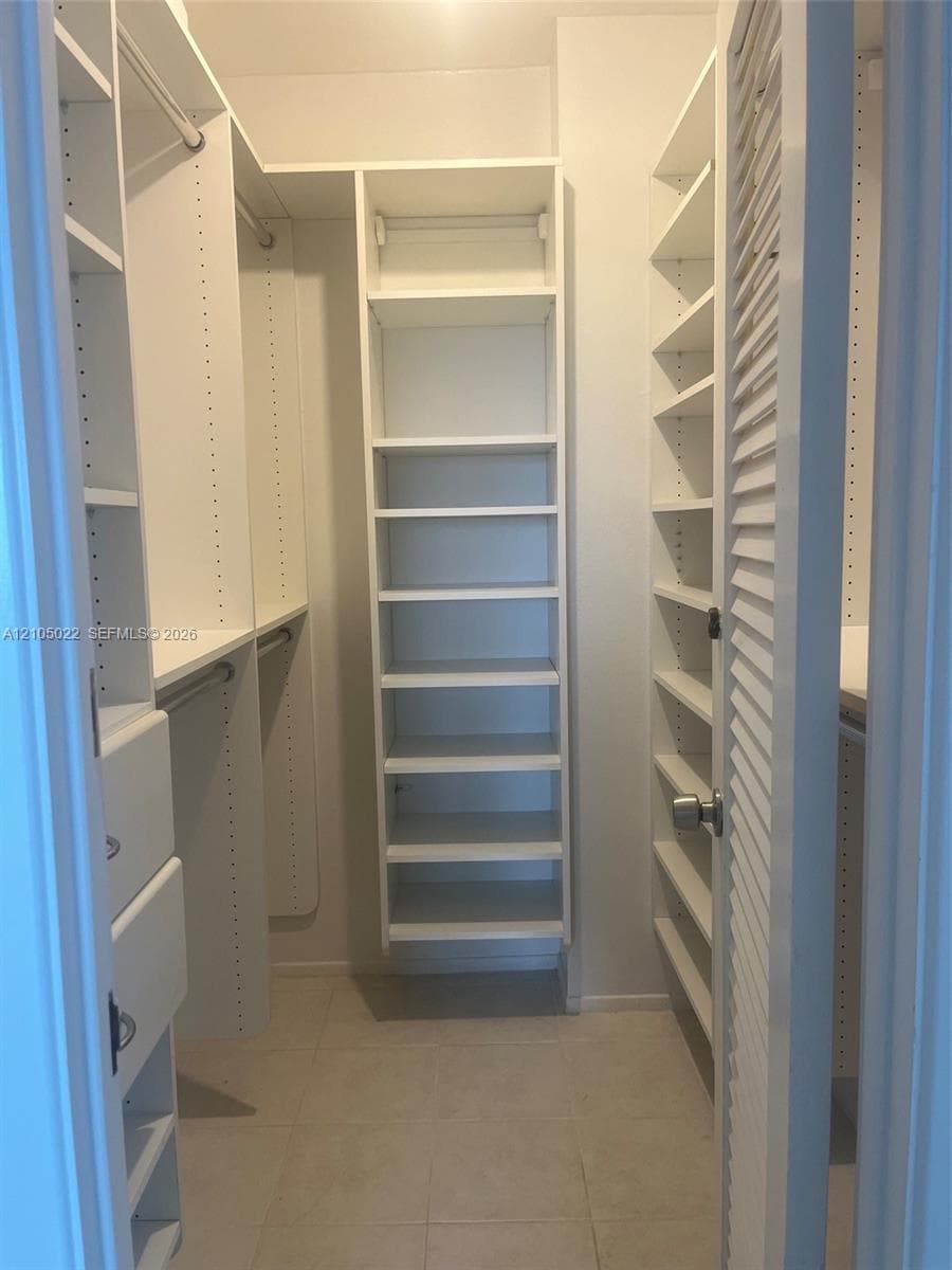Custom closet system featuring white shelving units, integrated drawers, and hanging rods