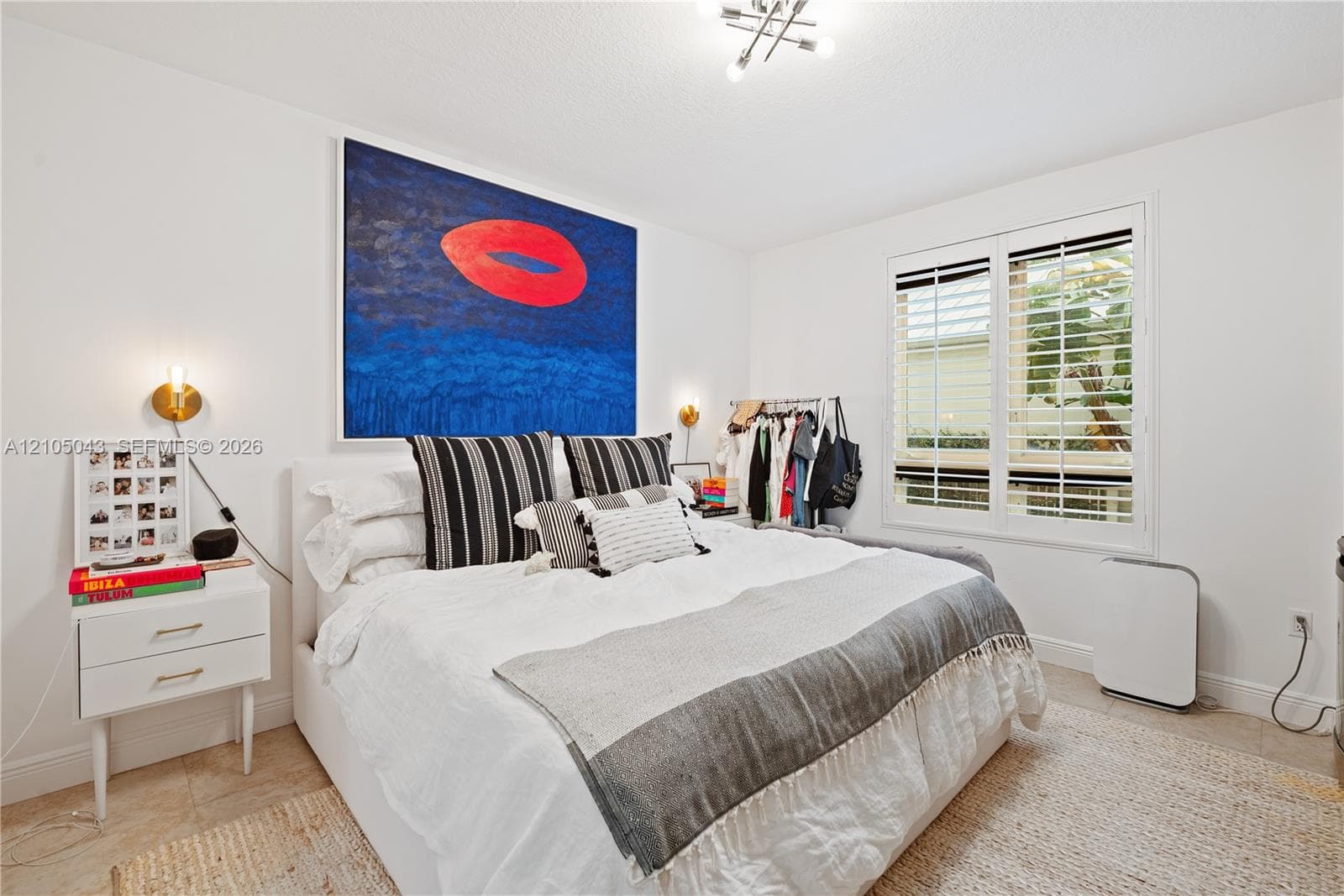 Interior space featuring white walls, a dual-sconce wall lighting fixture, a multi-bulb ceiling fixture, and plantation shutters