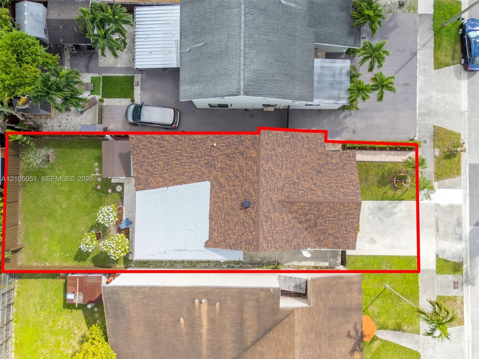 Aerial perspective of property lot featuring an expansive backyard, a multi-textured roofline, a private wood fence, and a concrete driveway