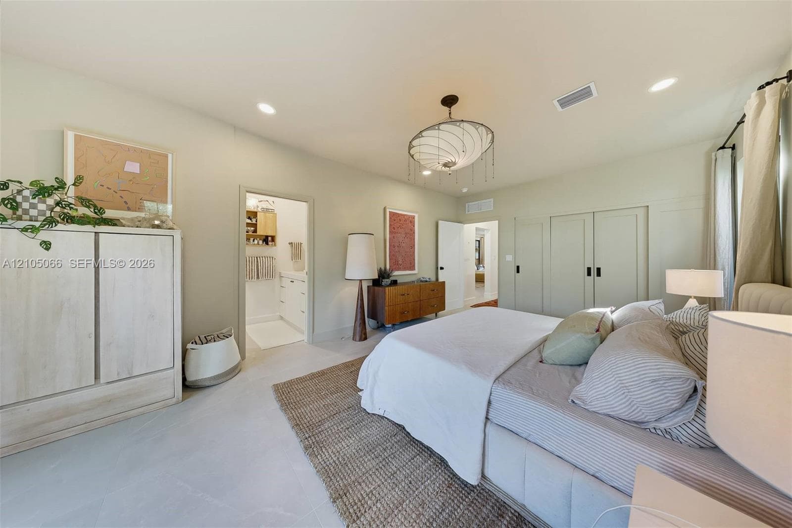 Bedroom featuring light-toned large-format tile flooring, recessed lighting, a modern multi-tiered chandelier, and floor-to-ceiling built-in cabinetry with matte black hardware