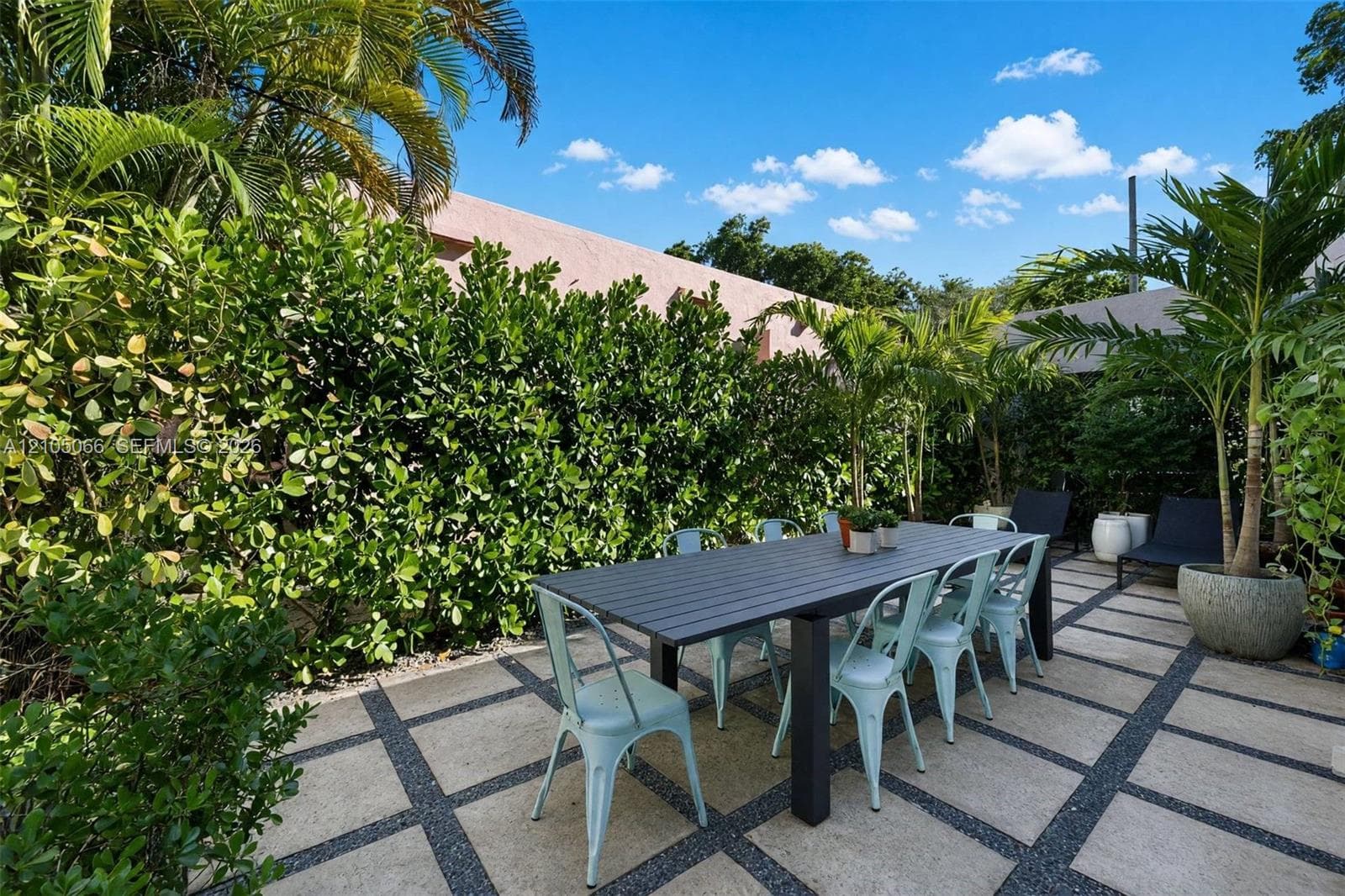 Rear patio featuring large-format stone pavers, geometric gravel inlay, and established perimeter hedges