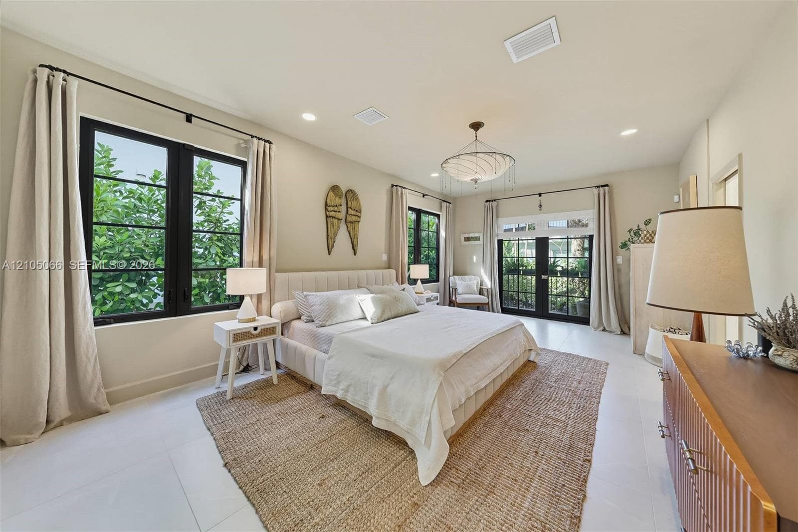 Neutral interior featuring large-format tile flooring, recessed lighting, a modern multi-tiered chandelier, black-framed windows, and a set of glass-paned double doors