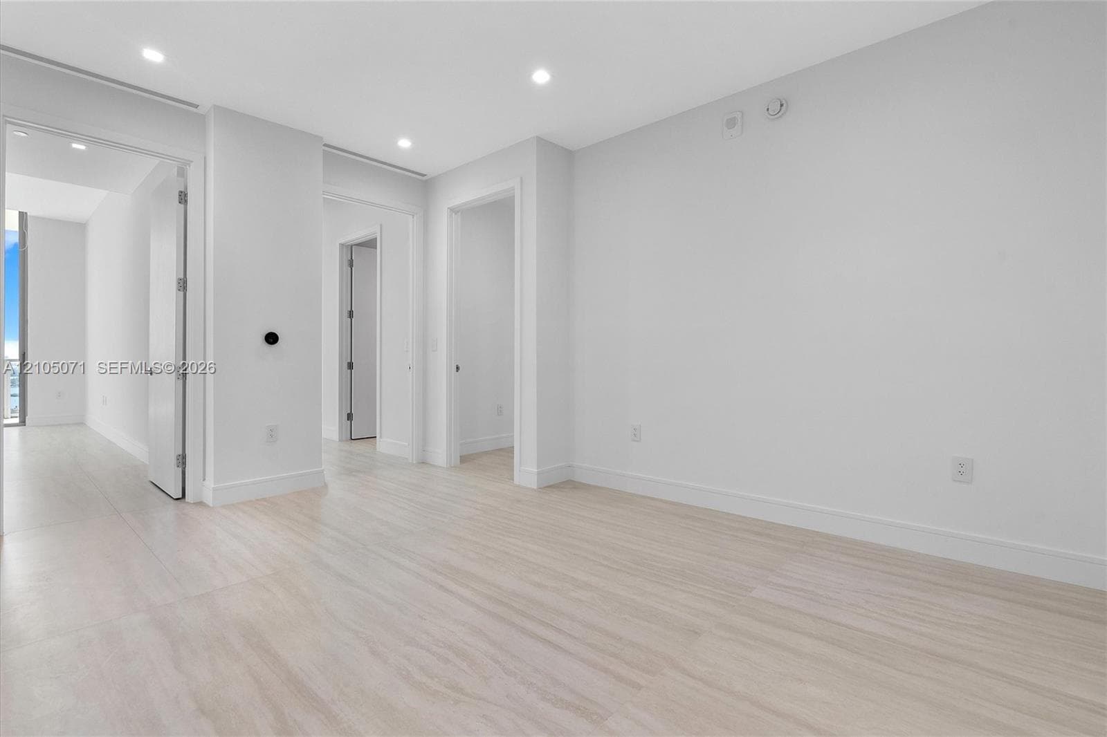 Neutral interior featuring light wood-finish flooring, recessed ceiling lighting, and crisp white wall finishes