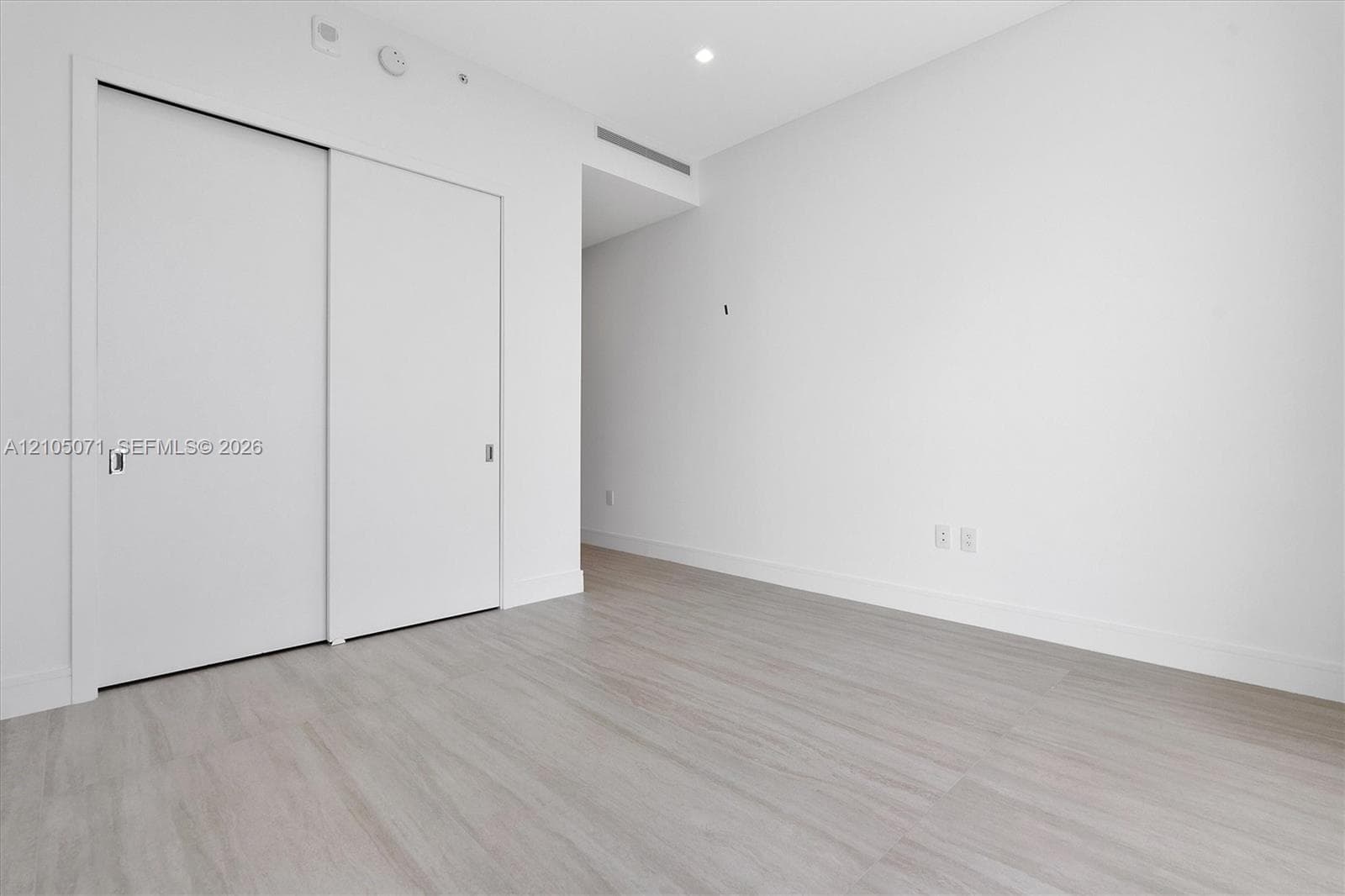 Interior space featuring wood-finish flooring, white walls, and a closet with sliding panel doors