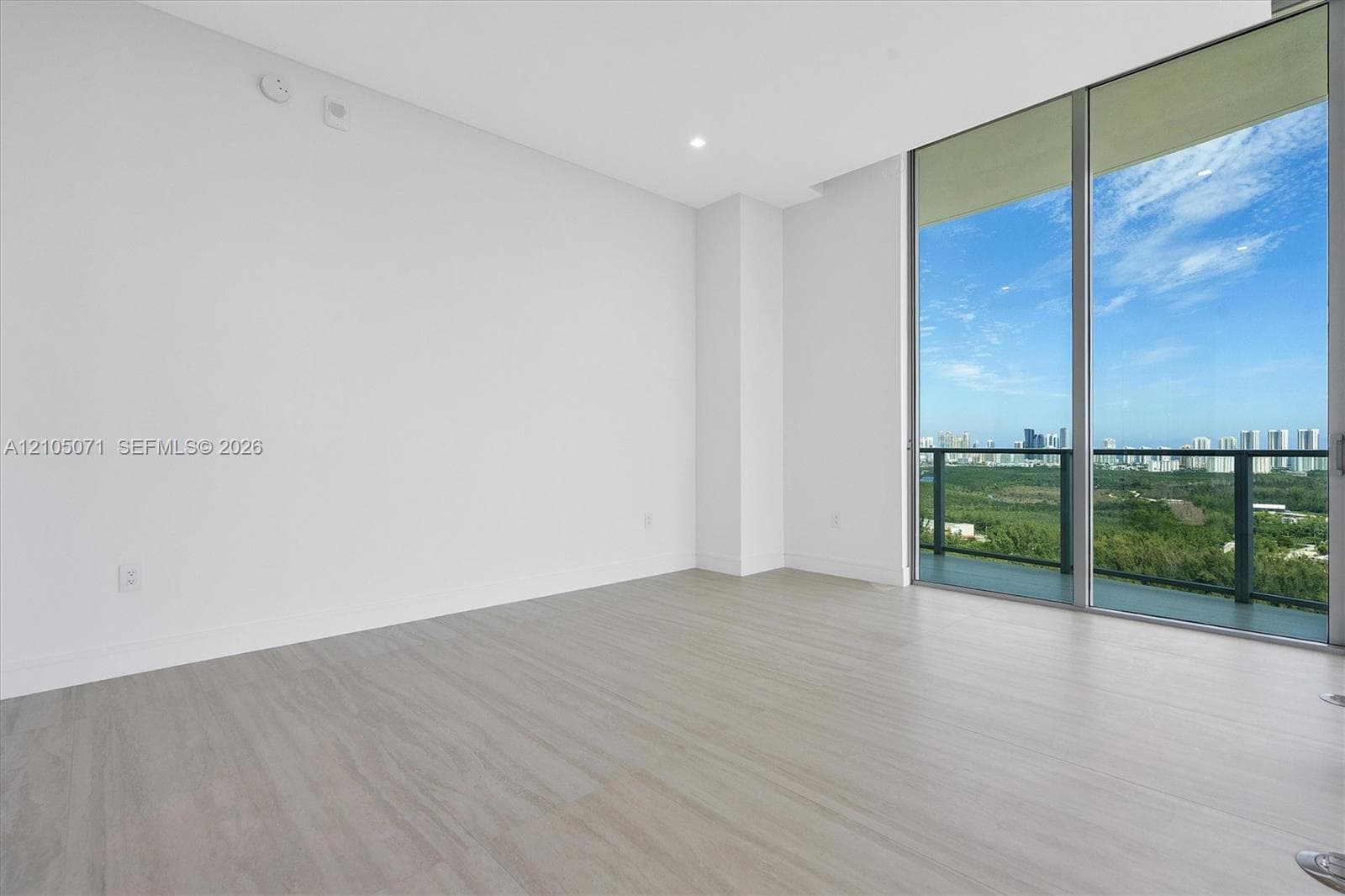 Floor-to-ceiling glass windows, wood-finish flooring, recessed lighting, and balcony with metal railing
