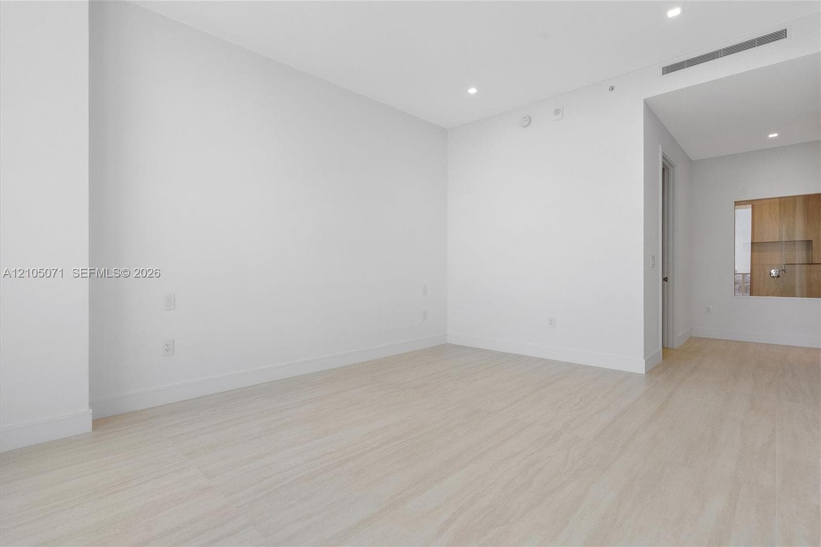 Neutral interior space featuring wood-finish flooring, recessed lighting, and a built-in cabinetry unit
