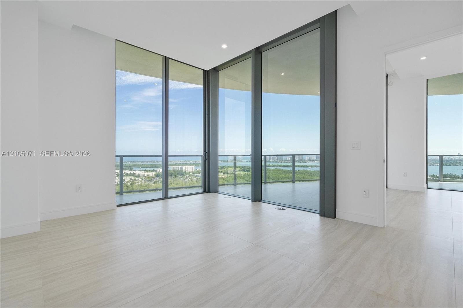 Floor-to-ceiling glass corner walls, expansive balcony, stone-finish flooring, and recessed ceiling lighting