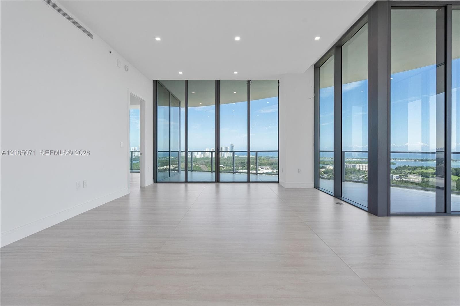 Floor-to-ceiling glass walls, expansive tile flooring, recessed lighting, and a wrap-around balcony with glass railings
