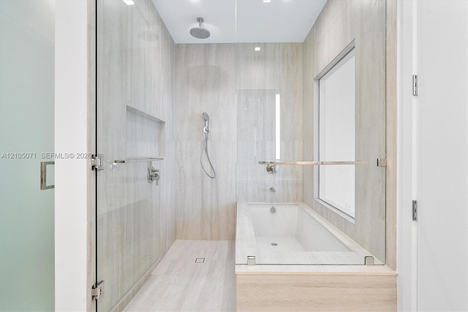 Walk-in shower and tub combination featuring floor-to-ceiling stone-finish tile, a rainfall showerhead, a handheld shower attachment, a recessed wall niche, and frameless glass enclosure