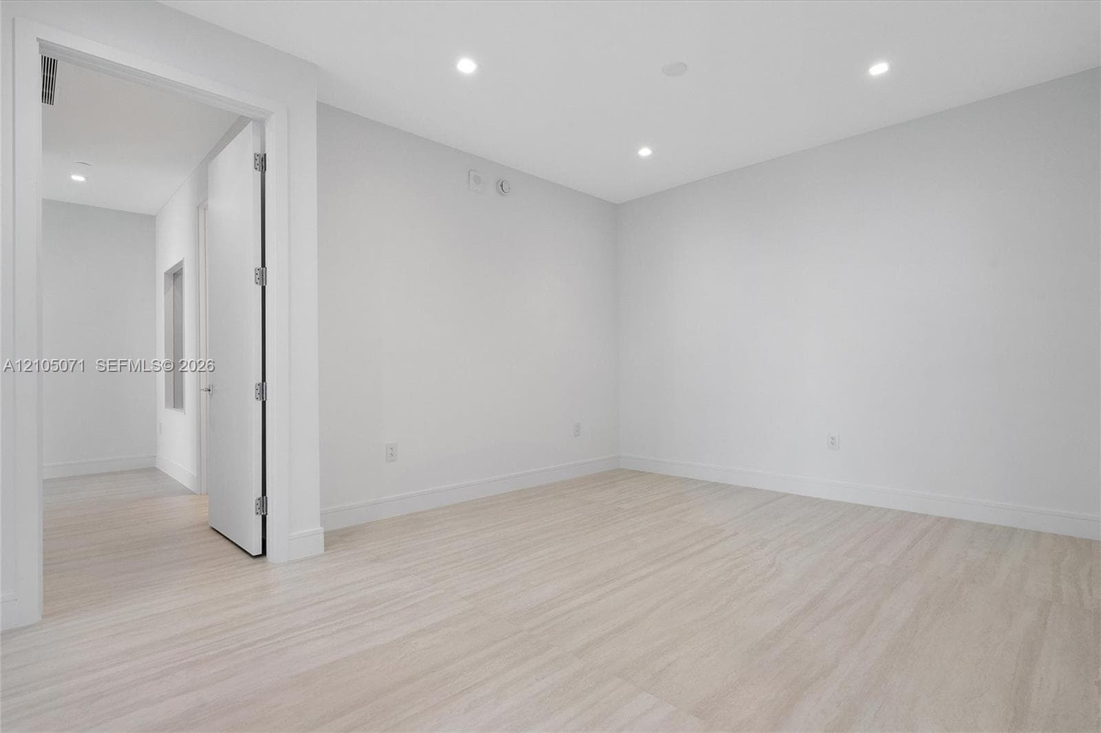 Neutral-toned interior featuring light wood-finish flooring, recessed lighting, and solid-core doors