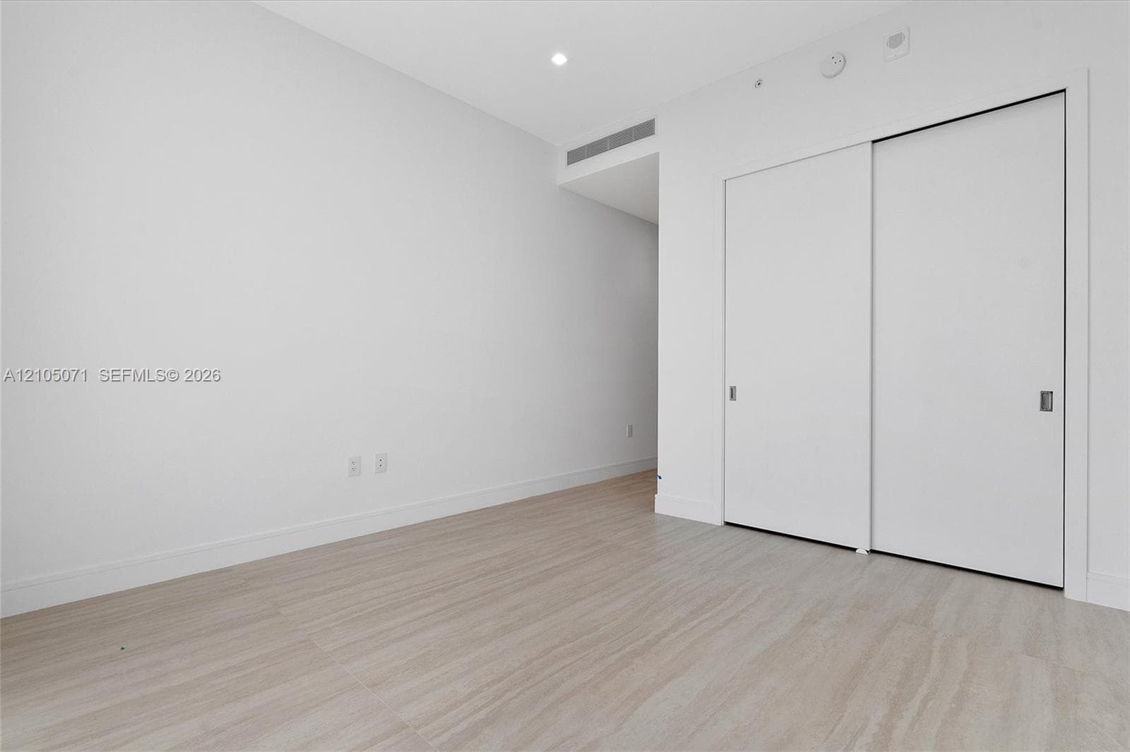 Interior space featuring light-toned wood-finish flooring, recessed ceiling lighting, and a closet with white sliding doors