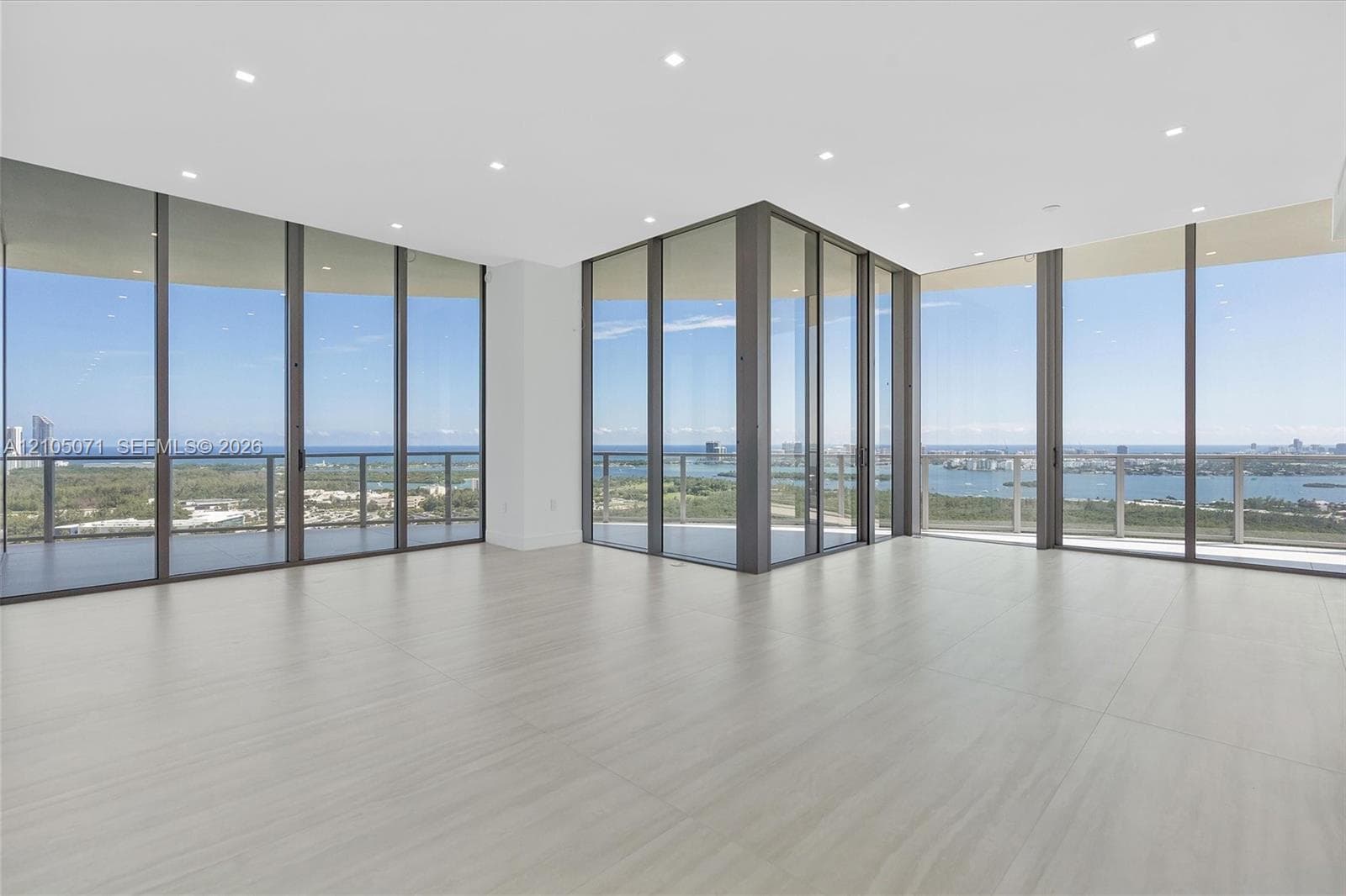 Floor-to-ceiling glass walls, large-format tile flooring, recessed ceiling lighting, and wraparound balcony with metal railings