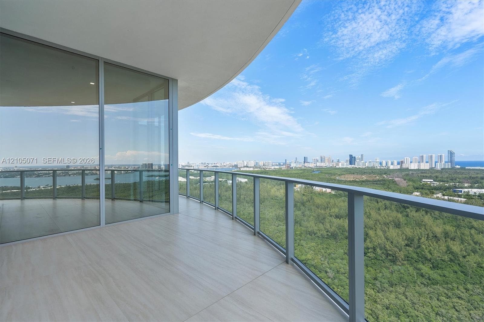 Covered balcony featuring oversized tile flooring, full-height glass sliding doors, and a metal railing