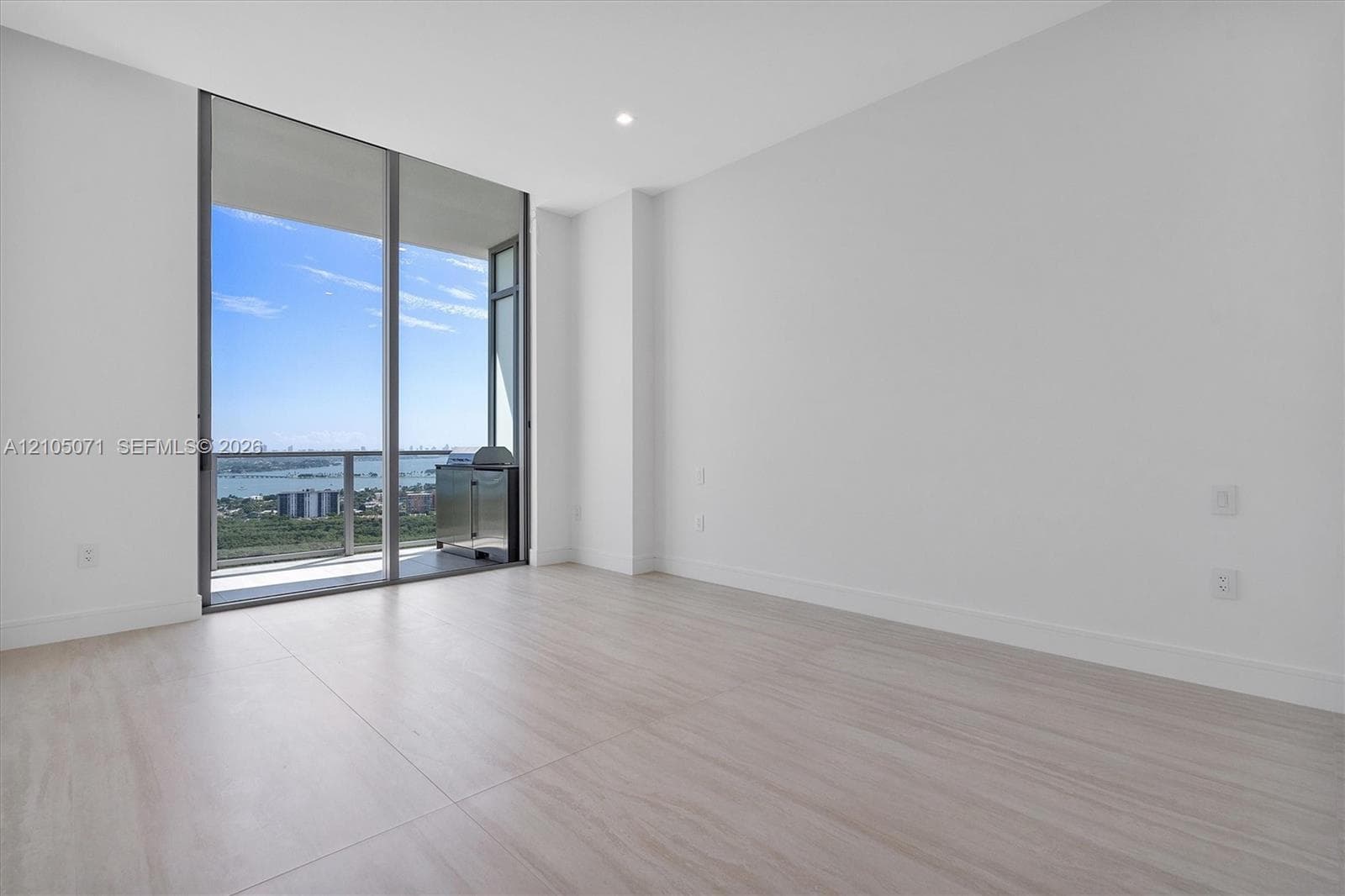 Floor-to-ceiling glass sliding doors, wood-finish tile flooring, recessed ceiling lighting, and a private balcony with metal railing