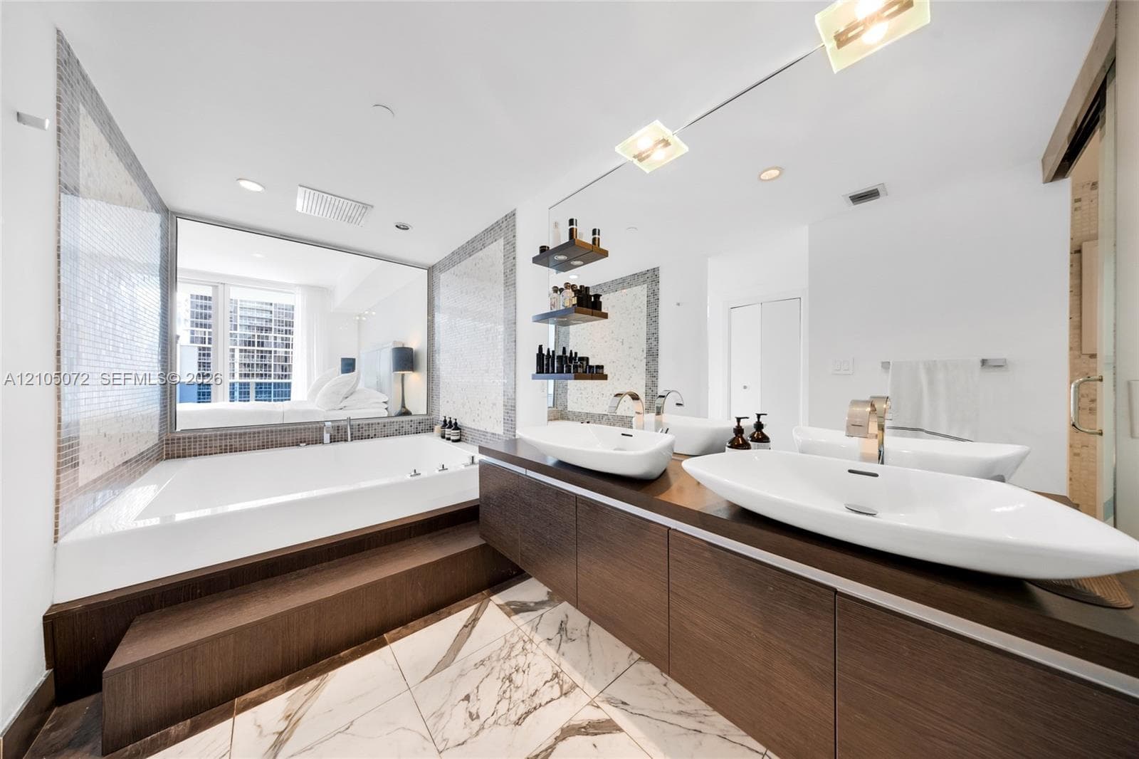 Primary bathroom with built-in tub, two vessel sinks, and a long wood-toned vanity.