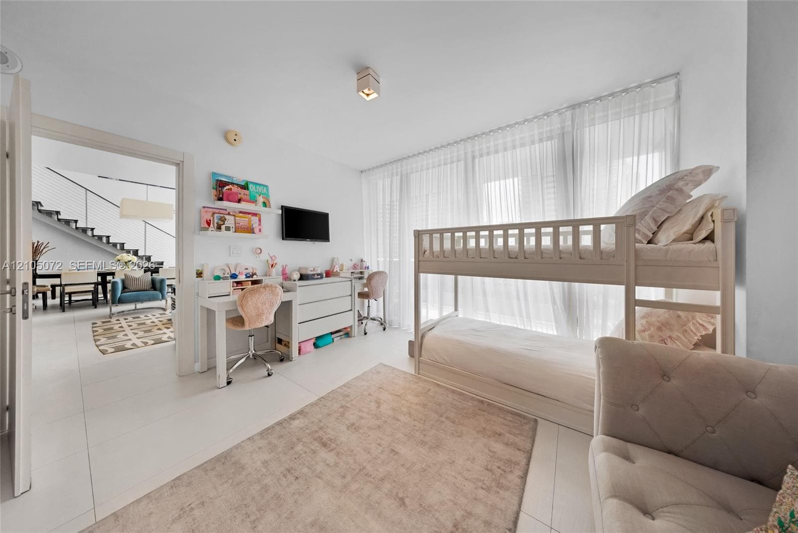 Secondary bedroom with bunk bed, study desk, and sheer curtains filtering daylight.