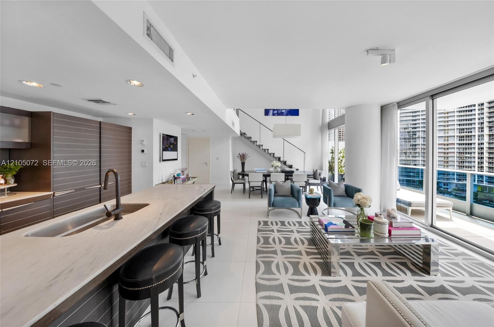 Kitchen island with Carrara marble counters and seating facing the open living room.