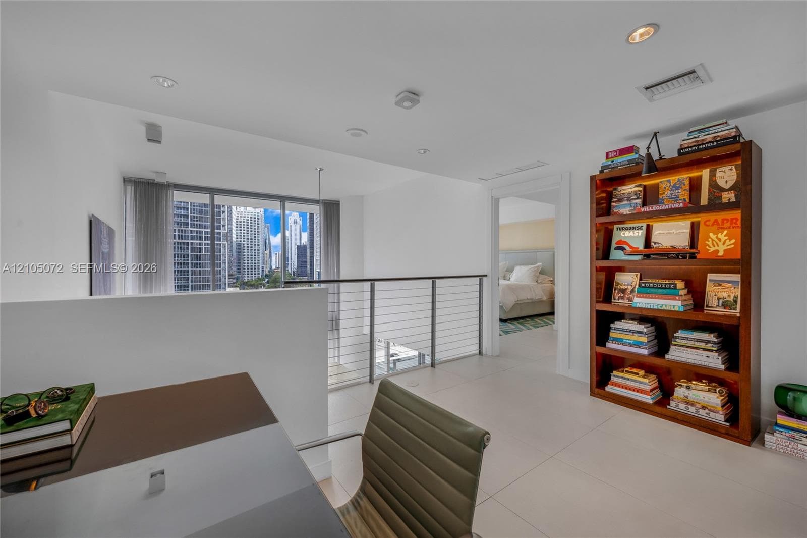 Upper-level den with desk, bookcase, cable railing, and passage to the primary bedroom.