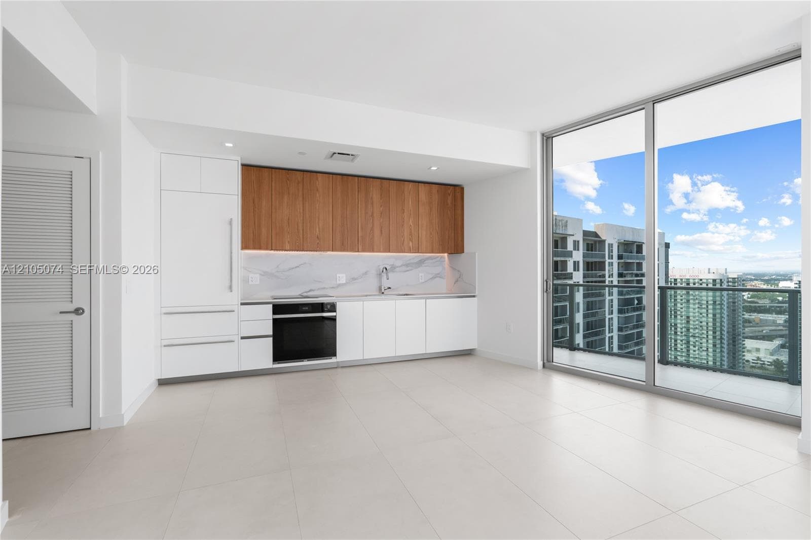 Wraparound balcony featuring large-format tile flooring, a glass panel railing, and full-height glass sliding door access