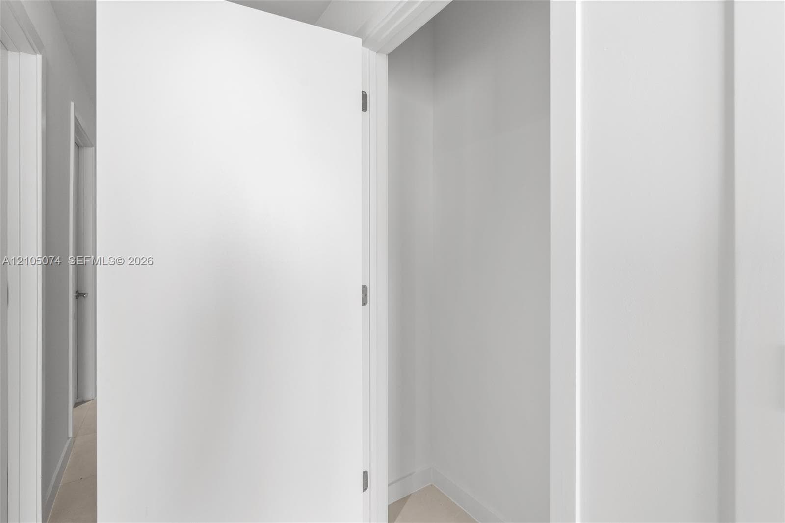 Interior closet featuring a clean, white-painted finish, smooth door paneling, and brushed nickel hardware