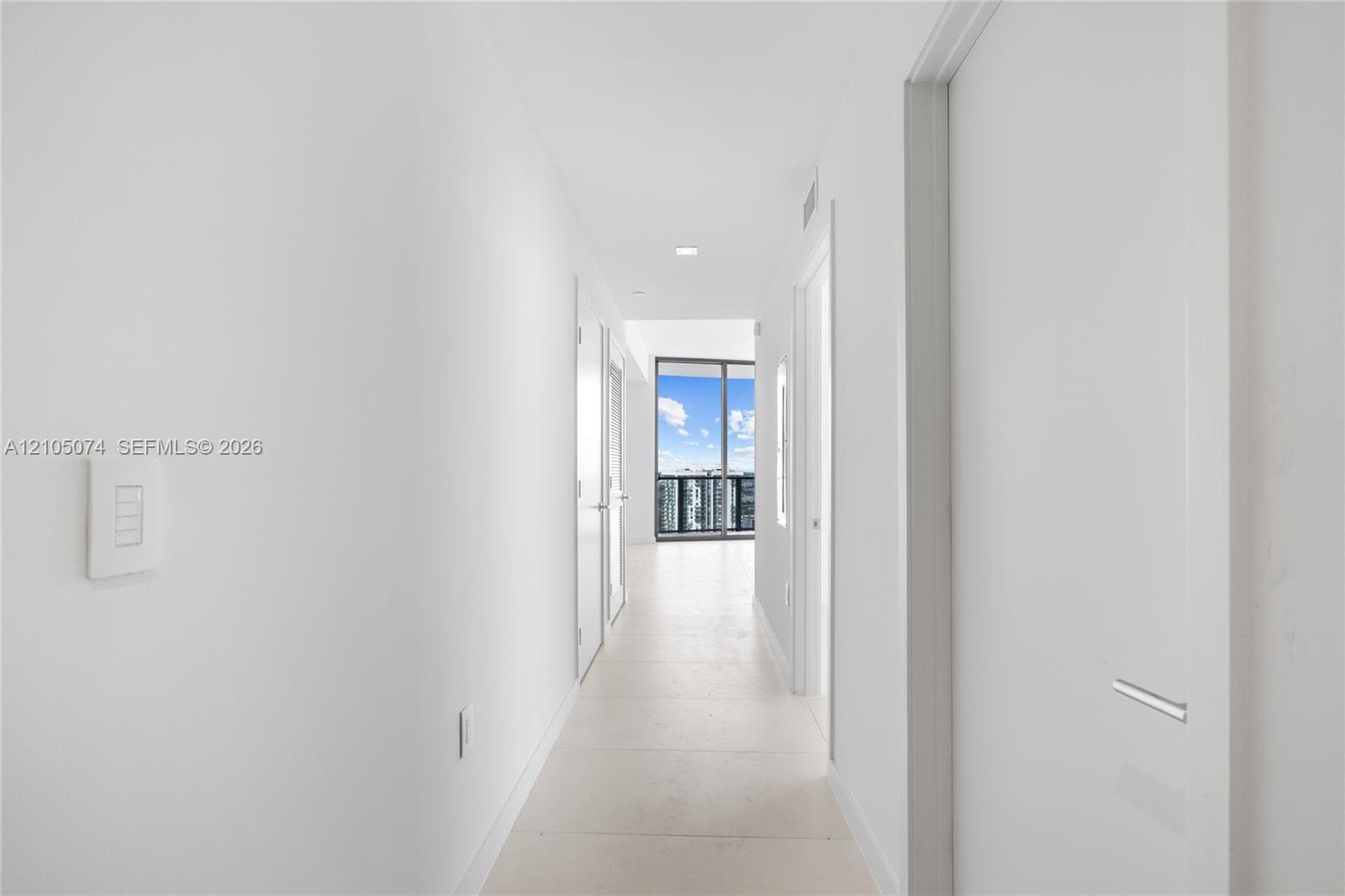 Covered balcony featuring expansive tile flooring and a glass railing system with a metal frame