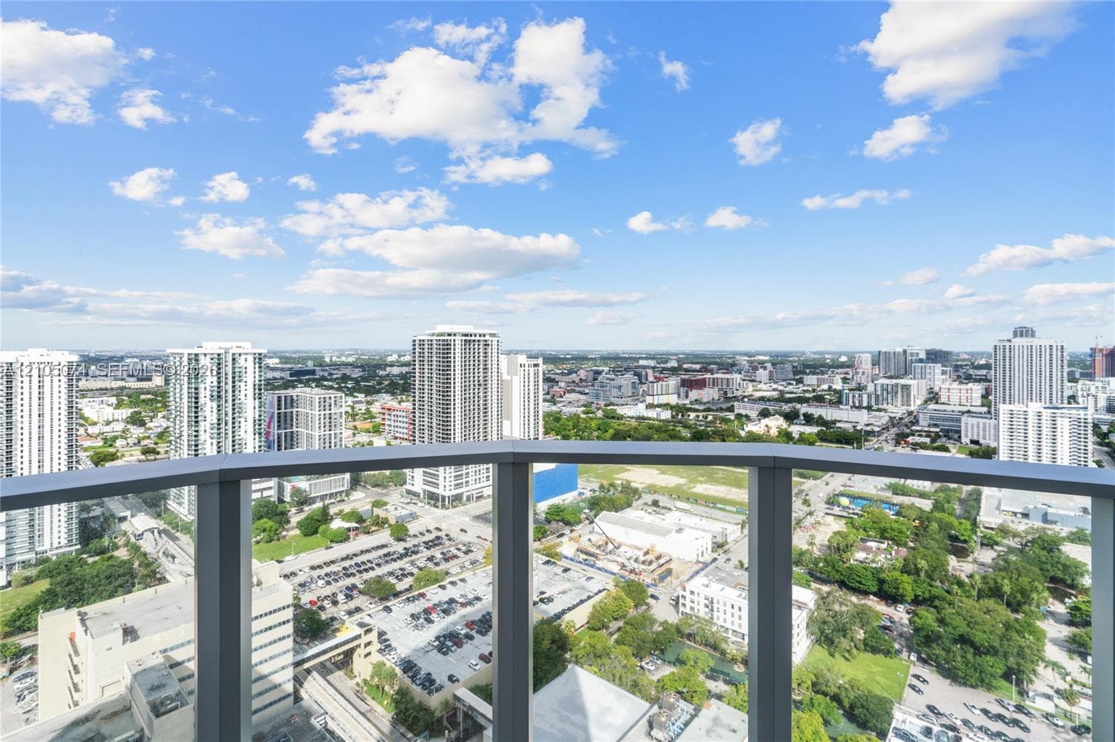 Floor-to-ceiling glass walls, wrap-around balcony access, large-format tile flooring, and neutral interior finishes