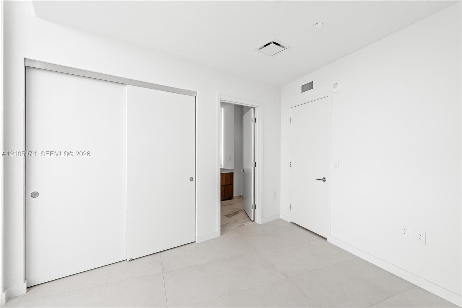 Hallway featuring neutral-toned tile flooring, recessed ceiling lighting, and floor-to-ceiling glass sliding doors