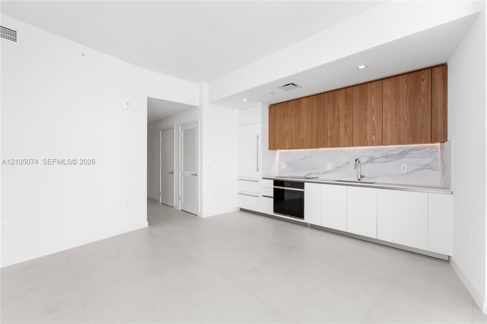 Stacked front-load washer and dryer unit, louvered closet door, and electrical panel access