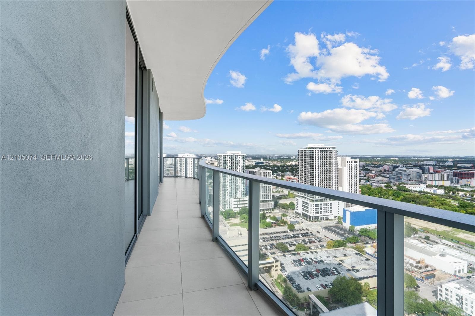 Curved exterior balcony featuring tile flooring, floor-to-ceiling glass paneling, and a structural railing
