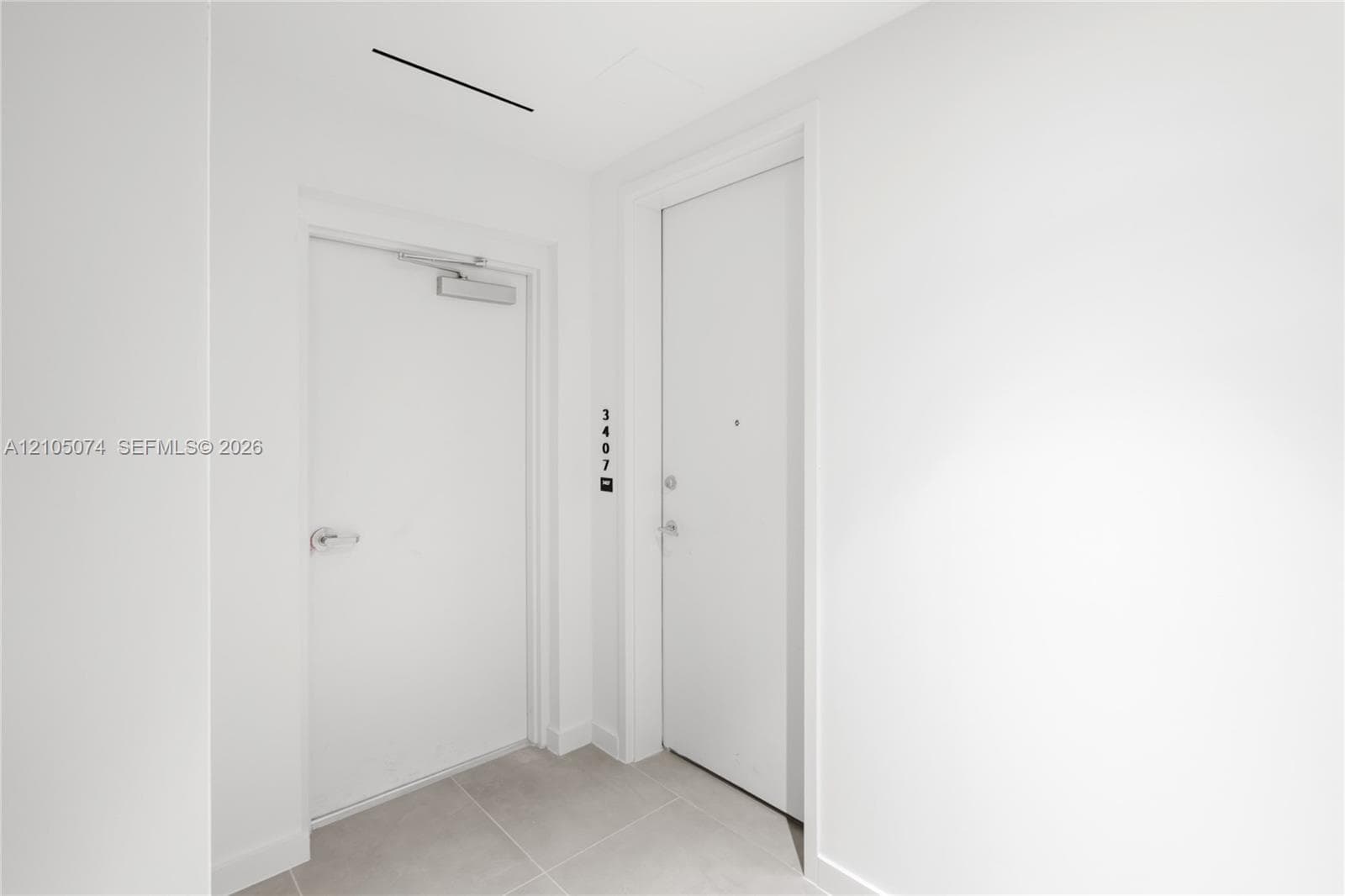 Entryway featuring solid-core doors, neutral large-format tile flooring, and integrated door hardware